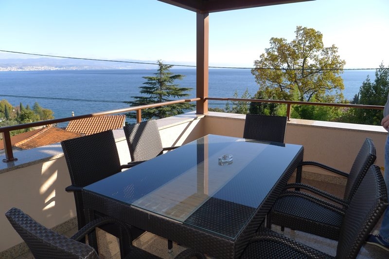 Terrasse couverte avec table en verre et vue sur la baie