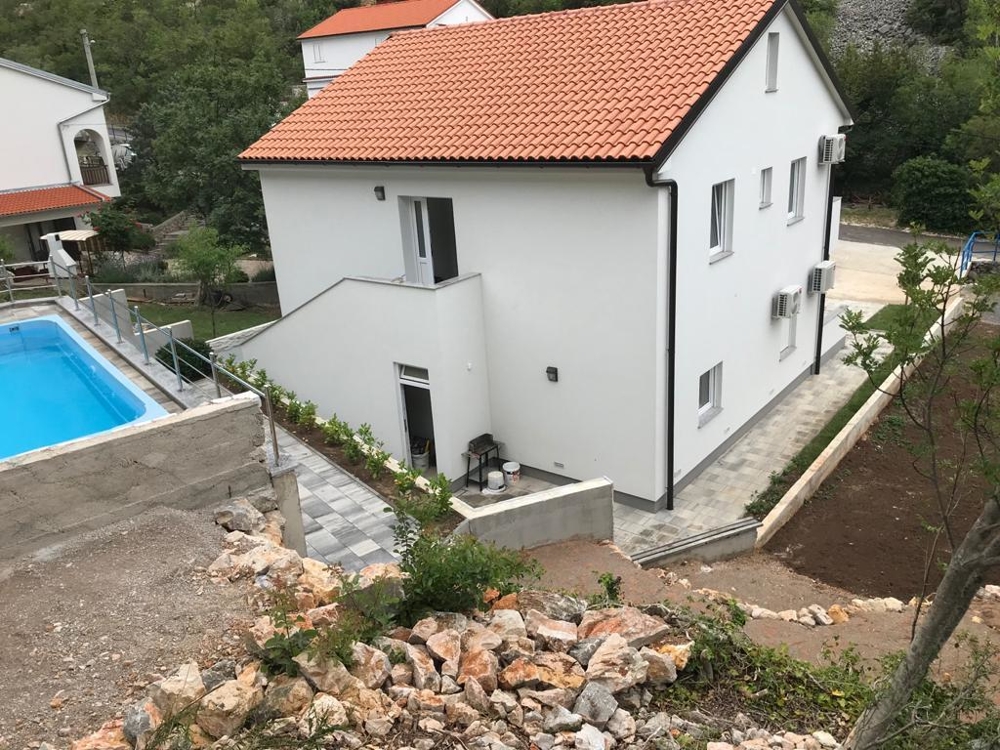 Maison avec terrasse et piscine derrière la maison.
