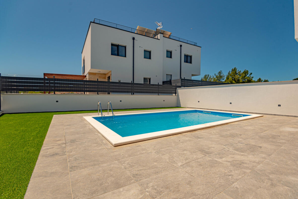 Piscine dans le jardin devant la maison jumelée blanche