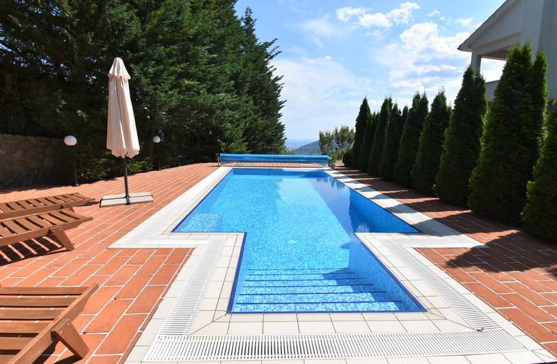Piscine avec parasol et cyprès en bordure