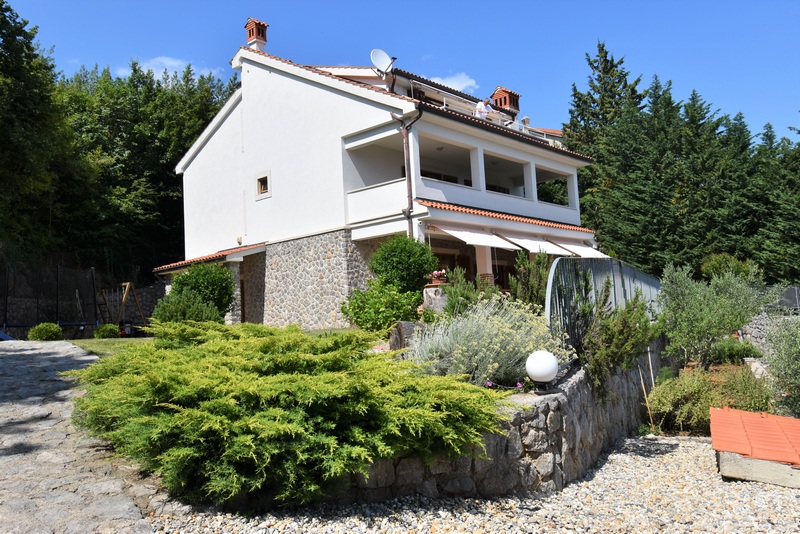 Maison blanche avec loggia derrière des buis et un mur en pierre sèche