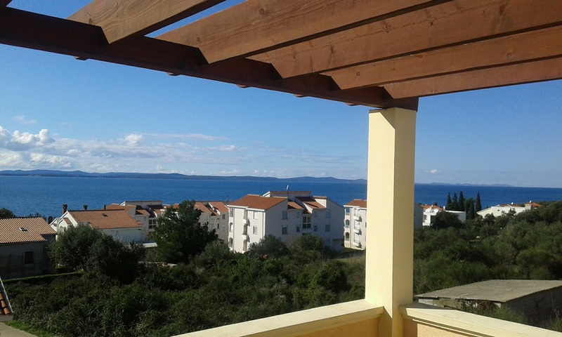 Pergola en bois au-dessus de la terrasse avec vue sur le village et la mer