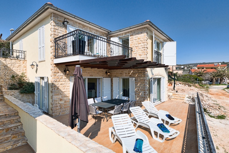 Maison à façade en pierre naturelle et transats sur la terrasse