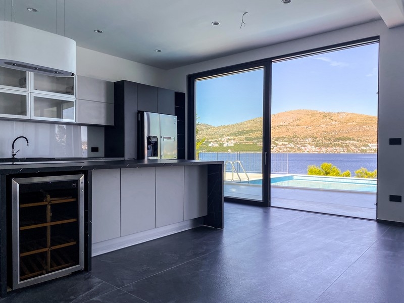 Cuisine moderne avec façade vitrée et vue sur la piscine et la mer
