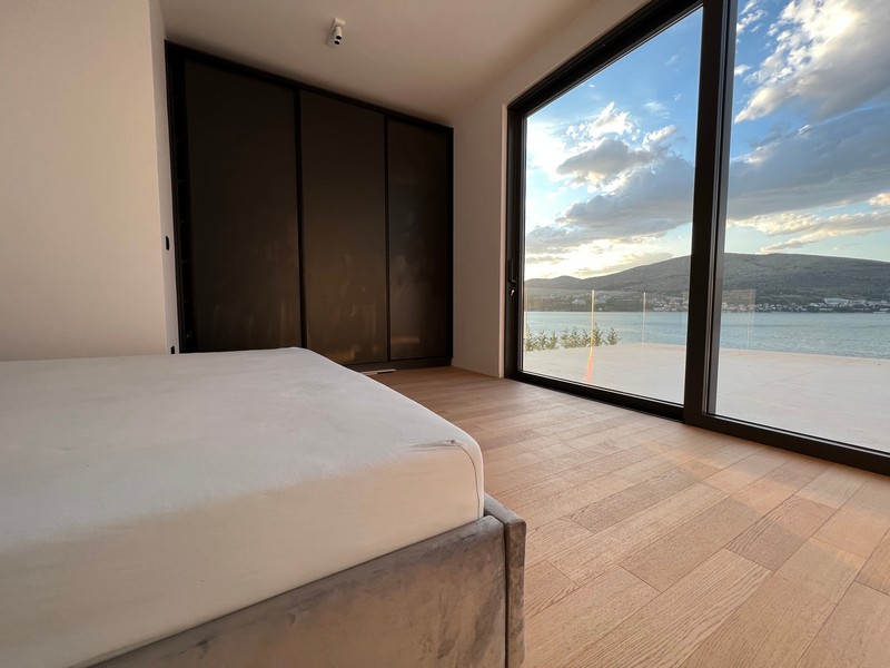 Chambre avec placard encastré et fenêtre du sol au plafond donnant sur la mer