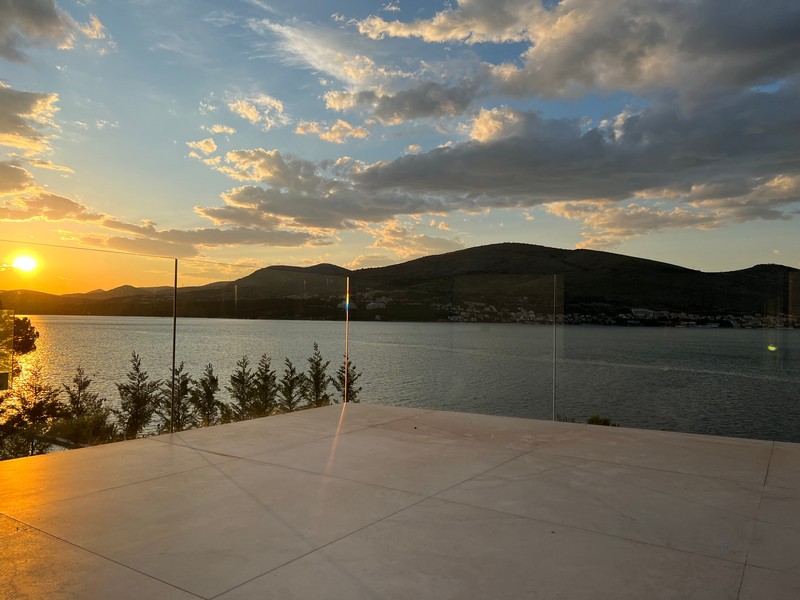 Terrasse avec garde-corps en verre au coucher du soleil sur la baie