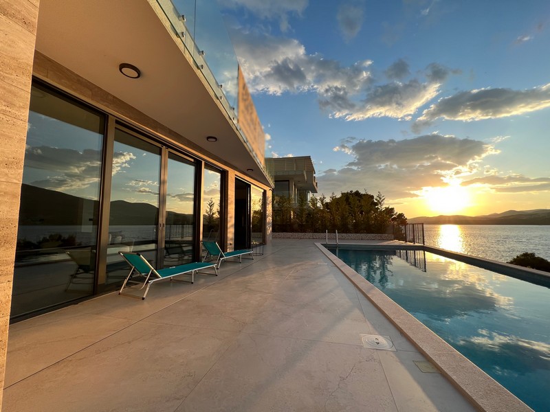 Piscine et transats le long de la façade vitrée à la lumière du soir