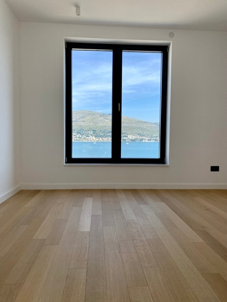 Pièce vide avec parquet et fenêtre donnant sur la baie