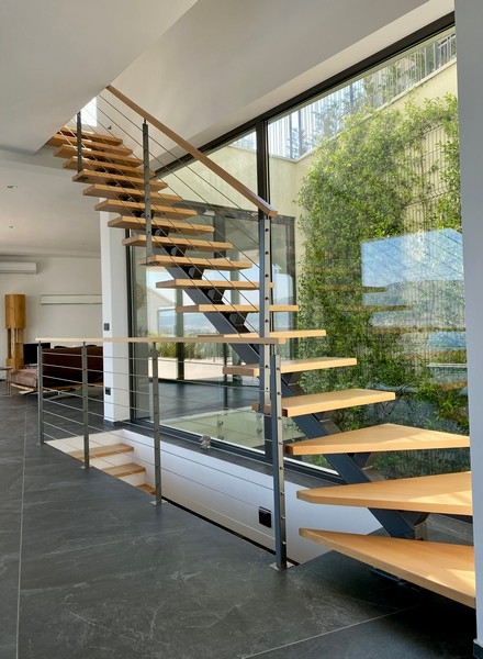 Escalier en bois autoportant devant la paroi vitrée végétalisée