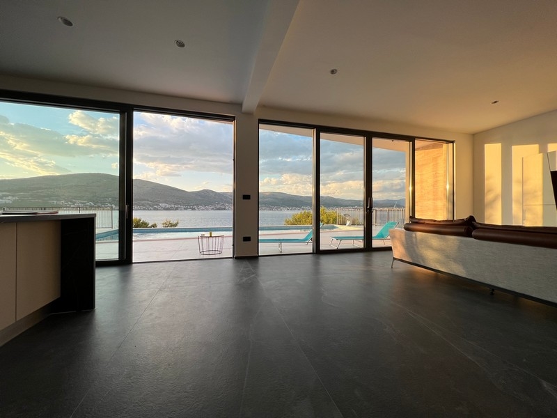 Séjour avec façade vitrée et piscine à la lumière du soir
