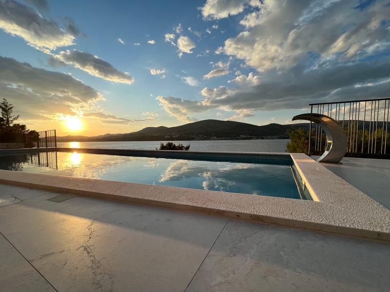Piscine à débordement au coucher du soleil au-dessus de la baie