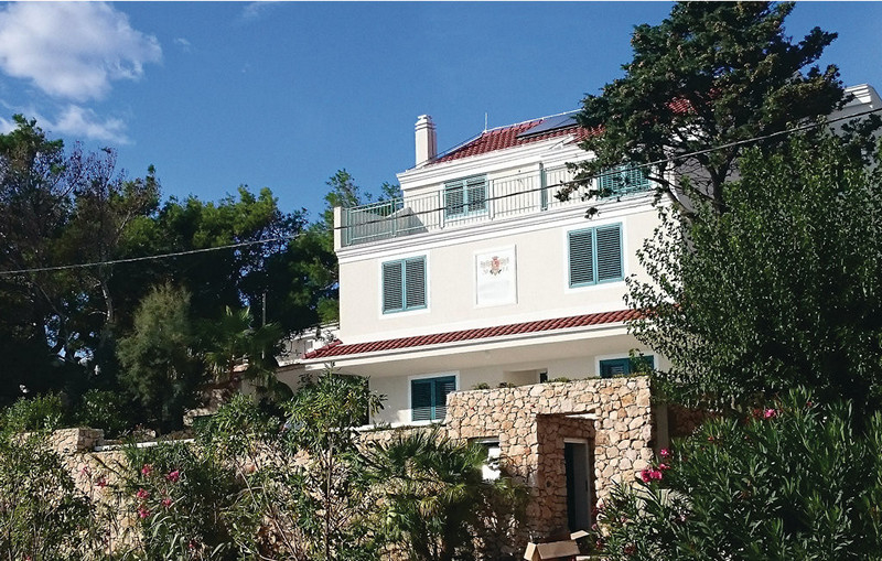 Maison blanche avec volets verts au-dessus du mur en pierre naturelle