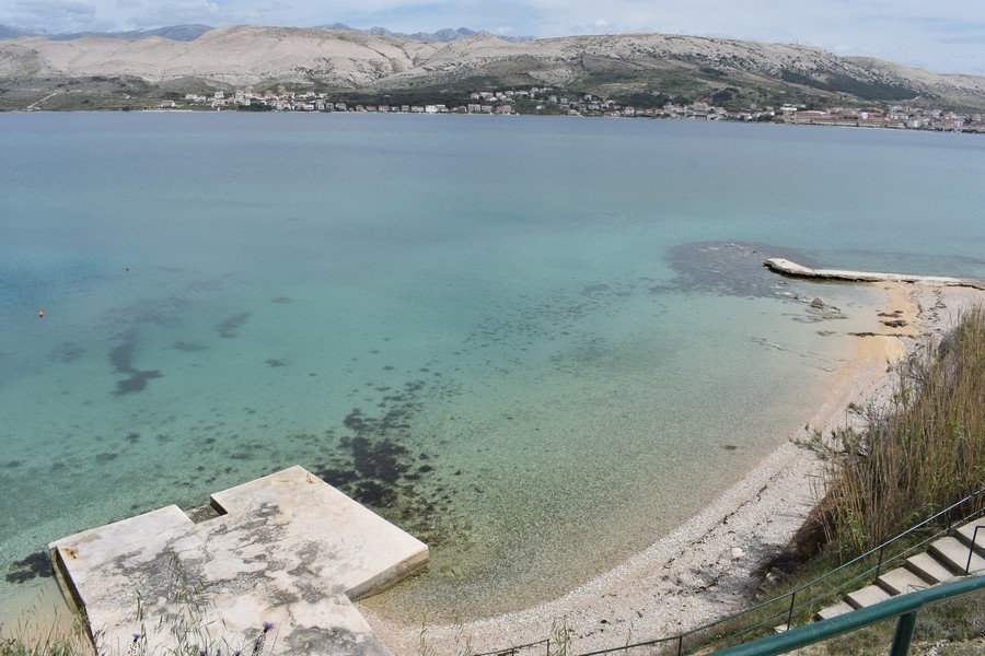 Baie peu profonde avec plage de galets et ponton en béton sur l'île de Pag