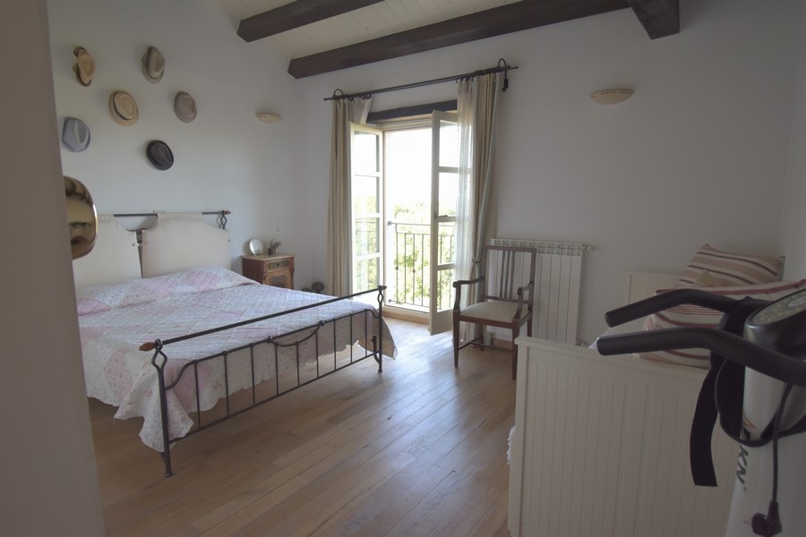 Chambre avec lit en fer et chapeaux au mur