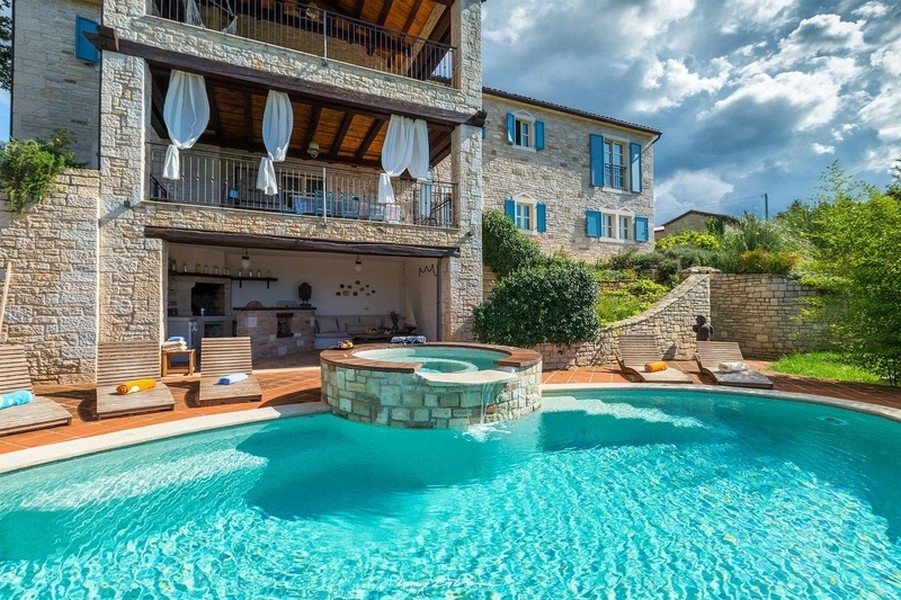 Piscine avec jacuzzi devant la maison en pierre aux volets bleus