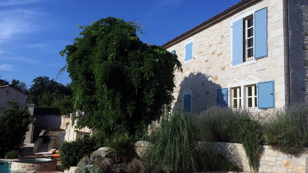 Façade en pierre naturelle avec volets bleus au-dessus du jardin