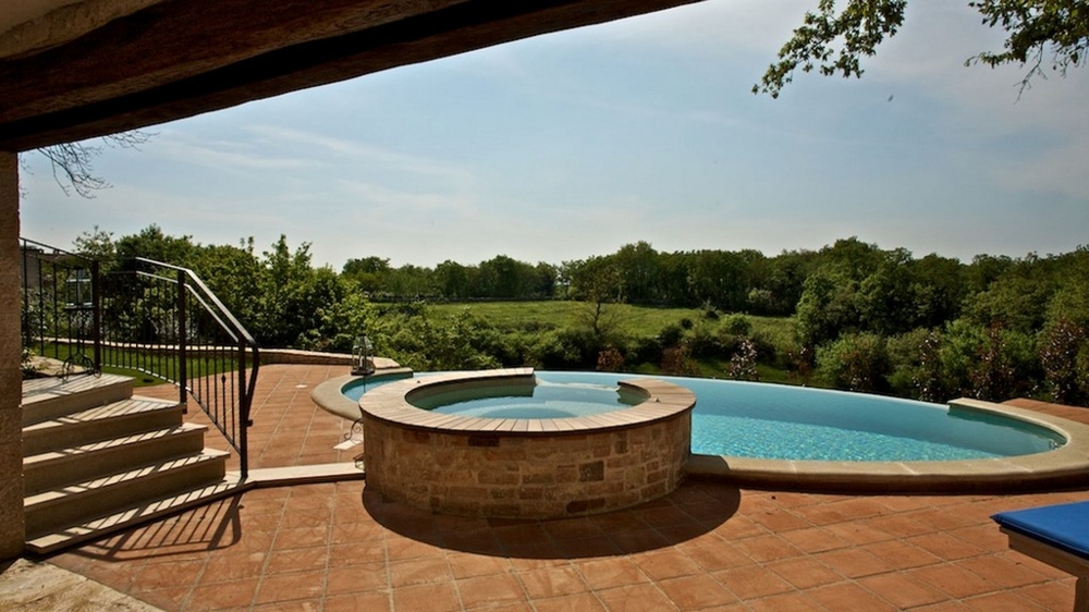 Jacuzzi rond et piscine sur la terrasse avec vue sur la verdure