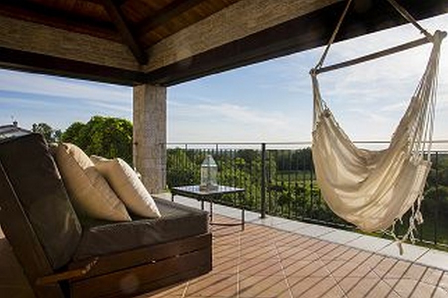 Terrasse couverte avec fauteuil suspendu et canapé au-dessus des champs