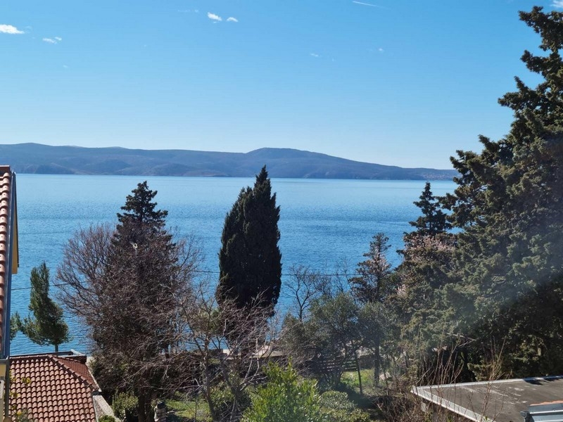 Vue entre des cyprès sur la mer et l'île de Krk