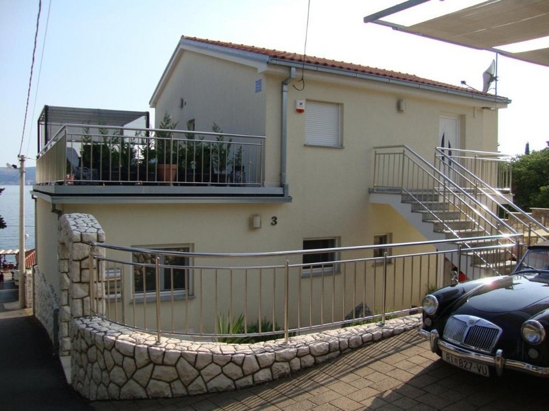 Maison avec escalier extérieur et balcon au-dessus du mur en pierre naturelle