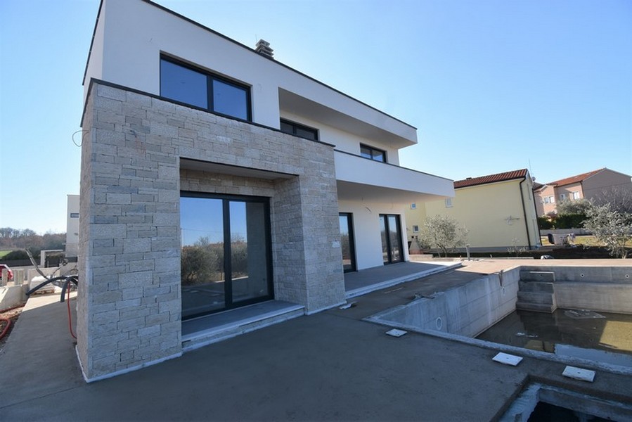 Construction neuve à façade en pierre naturelle et bassin de piscine en gros œuvre