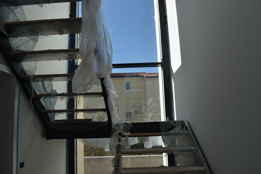 Escalier recouvert d'un film devant la haute baie vitrée