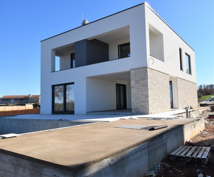 Vue latérale de la villa en pierre naturelle avec terrasse couverte