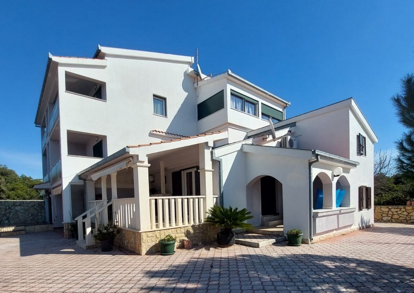 Immeuble d'appartements blanc avec véranda et cour d'entrée pavée