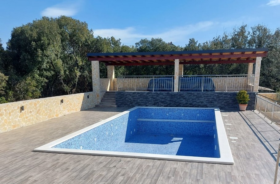 Piscine avec terrasse en bois et coin salon couvert derrière
