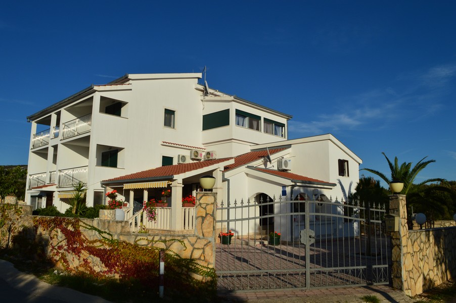 Bâtiment avec auvent en briques derrière le portail en fer forgé