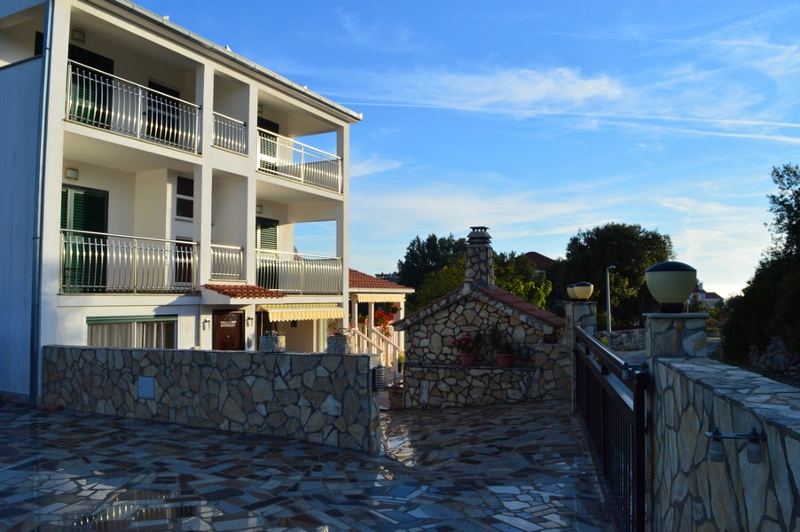 Cour dallée de pierres avec barbecue maçonné à côté de la maison