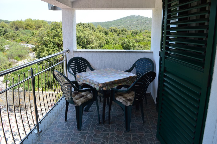 Balcon avec table et chaises devant des collines boisées