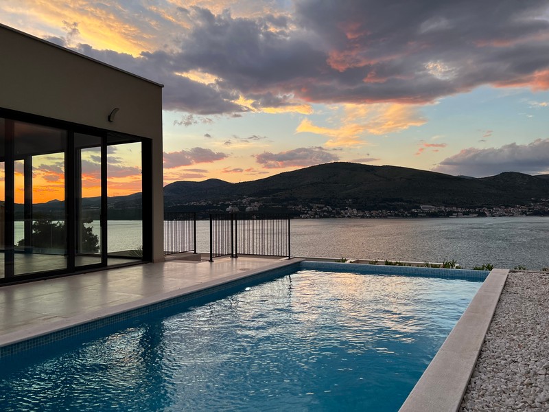 Piscine près de la maison au coucher du soleil sur la baie de Trogir