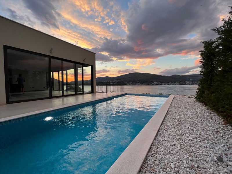 Longue piscine à côté de la façade vitrée à la lumière du soir