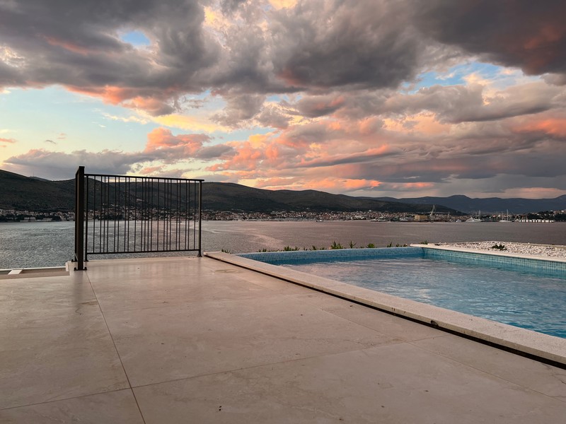 Bord de la piscine avec vue sur la baie sous des nuages roses du soir