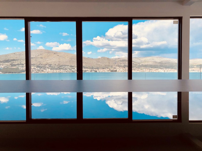Façade vitrée avec vue par-dessus la baie sur les collines