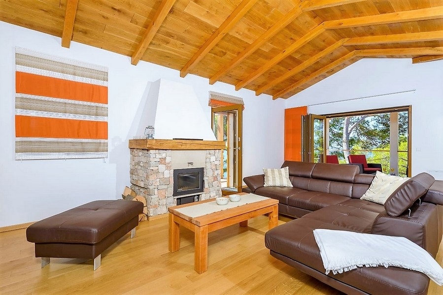 Salon avec plafond à poutres en bois et cheminée en pierre naturelle