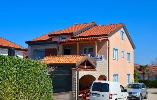 Maison en bande avec toit en tuiles et garage derrière la haie