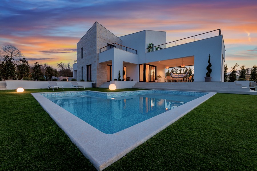Villa éclairée avec piscine dans la pelouse au crépuscule