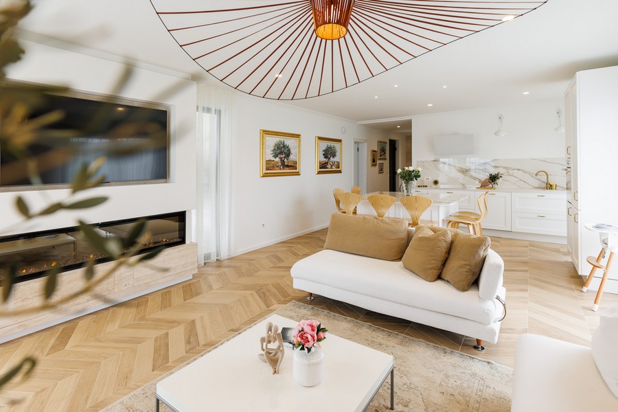 Séjour avec parquet à chevrons et canapé devant la cheminée