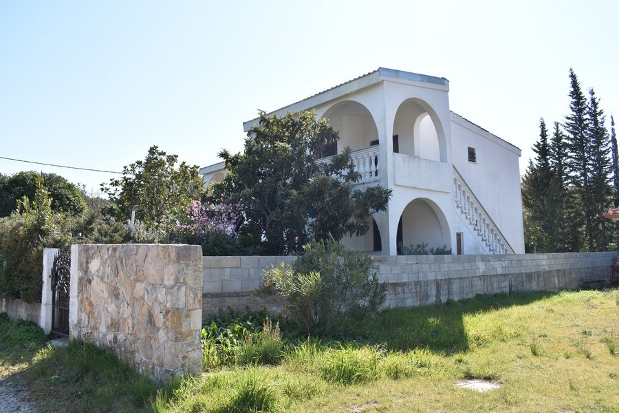 Maison avec arcades et escalier extérieur derrière le mur