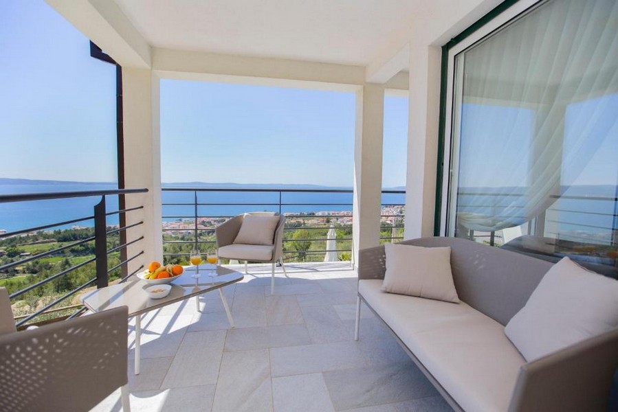 Balcon couvert avec canapé et vue sur le village jusqu'à la mer