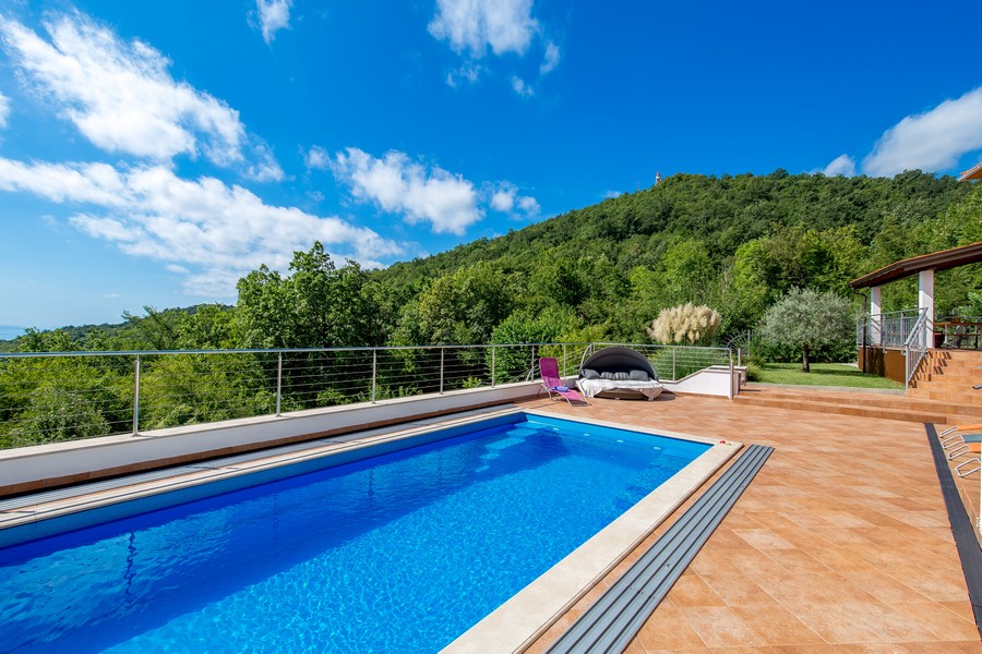 Piscine sur la terrasse carrelée devant des collines boisées