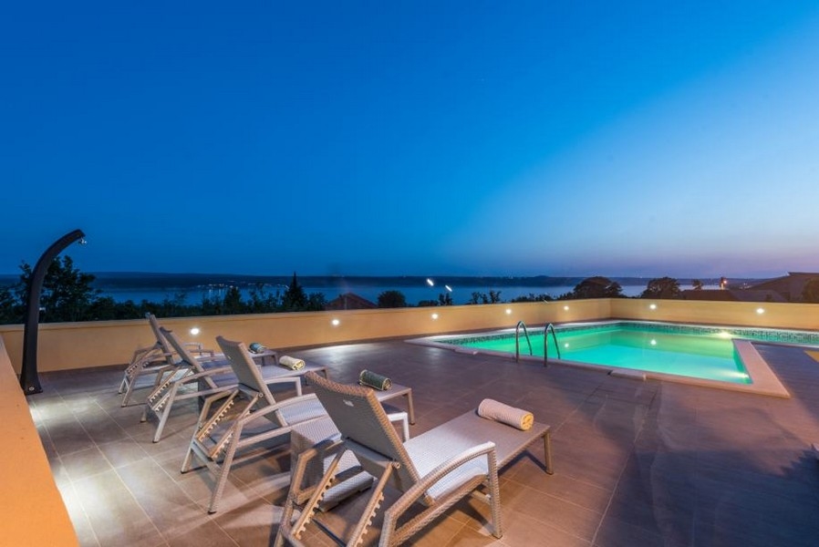 Piscine éclairée avec bains de soleil à l'heure bleue