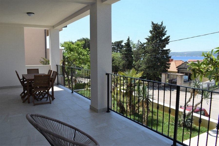Loggia avec table en bois et vue au-dessus des palmiers sur la mer