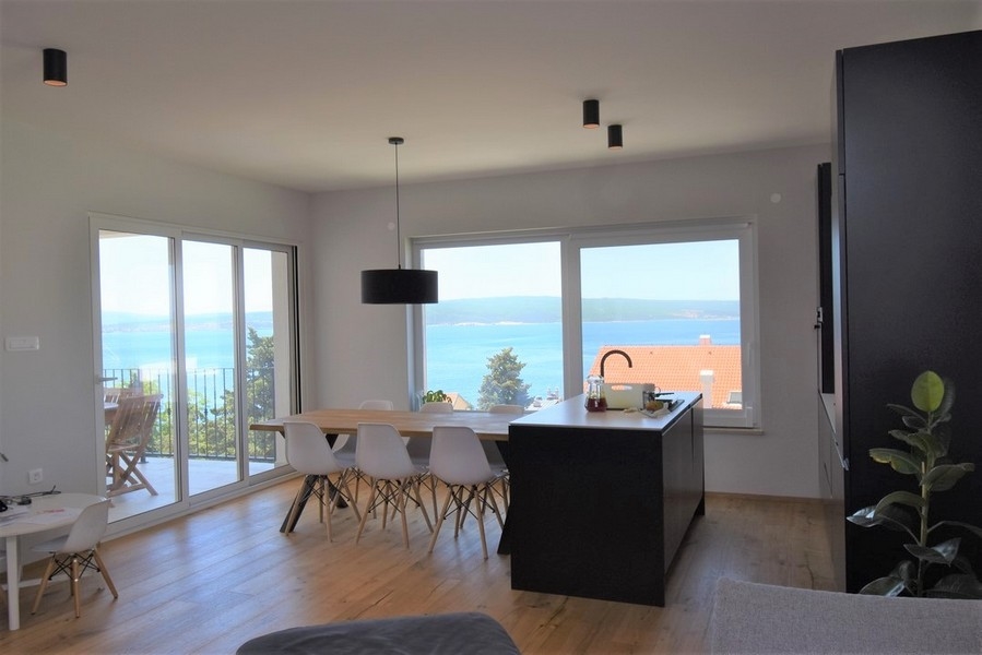Îlot de cuisson et table à manger devant les fenêtres donnant sur la baie