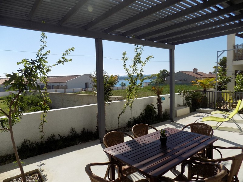 Terrasse sous la pergola avec table à manger et vue sur l'eau