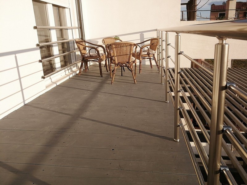 Balcon avec chaises en osier et garde-corps en inox