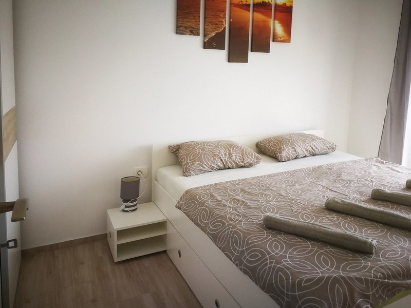 Chambre avec lit clair et tableaux au-dessus de la tête de lit