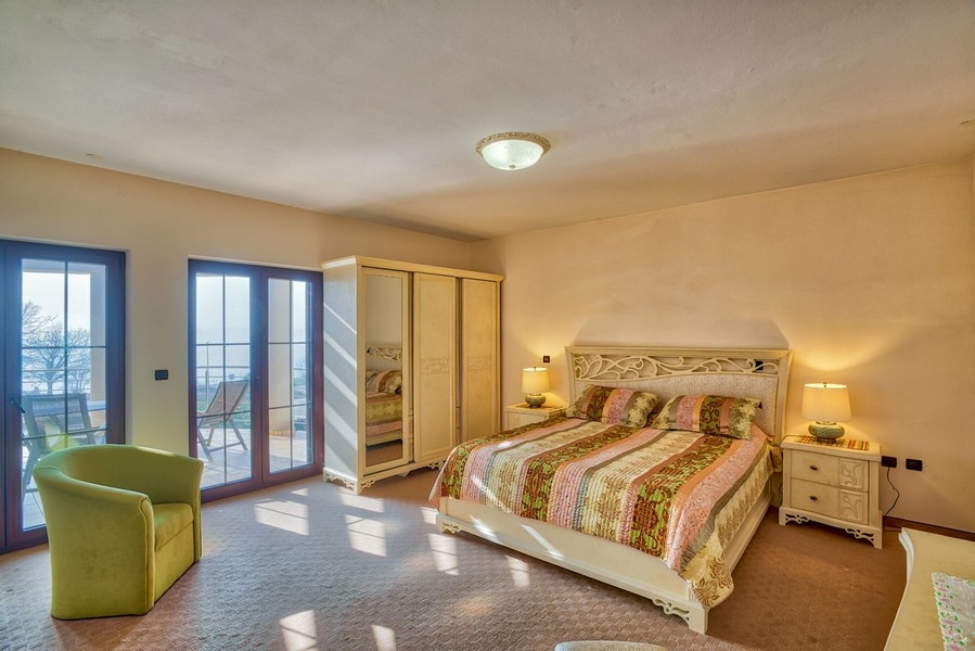 Grande chambre avec portes de balcon et fauteuil vert